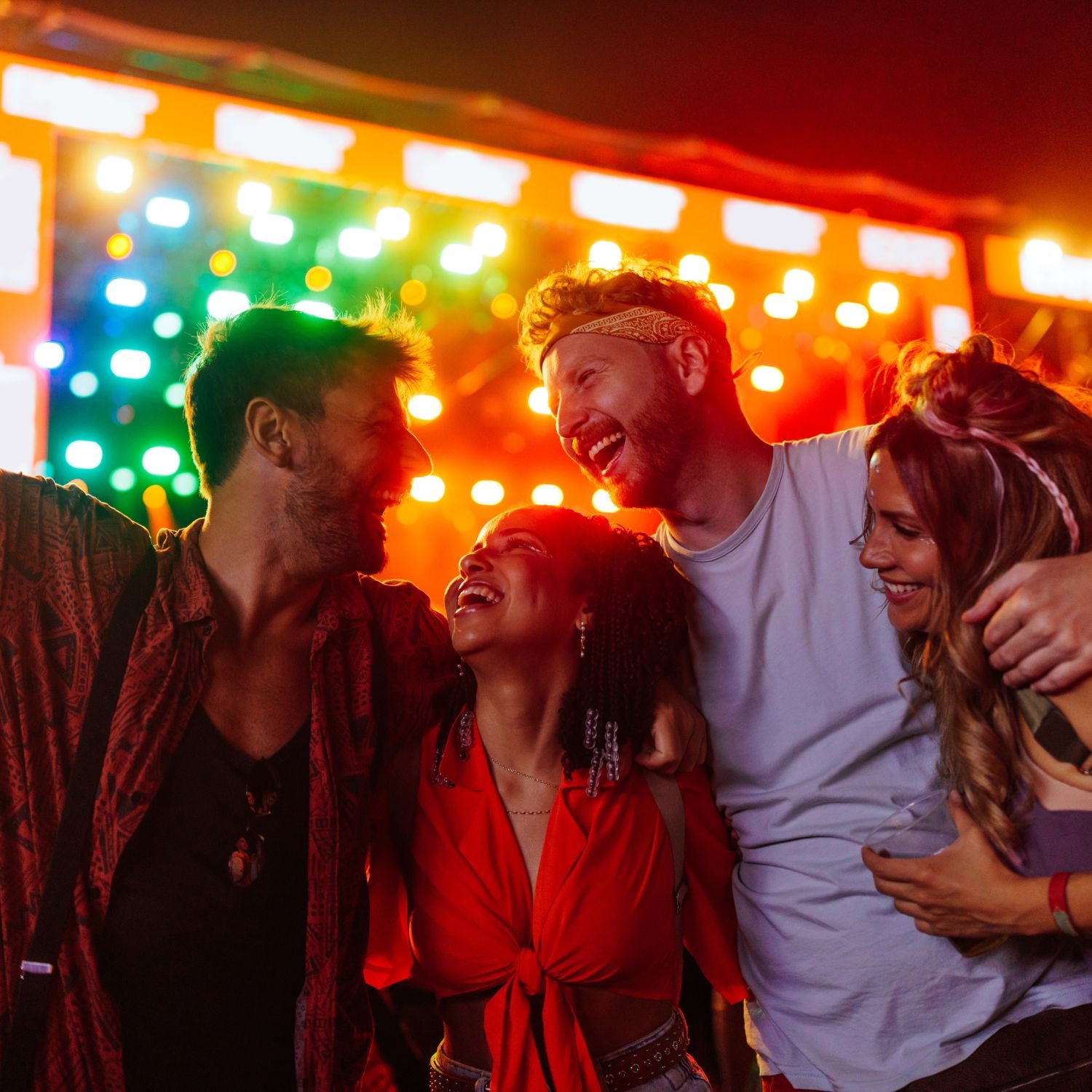 Group of friends laughing together with colorful lights in the background