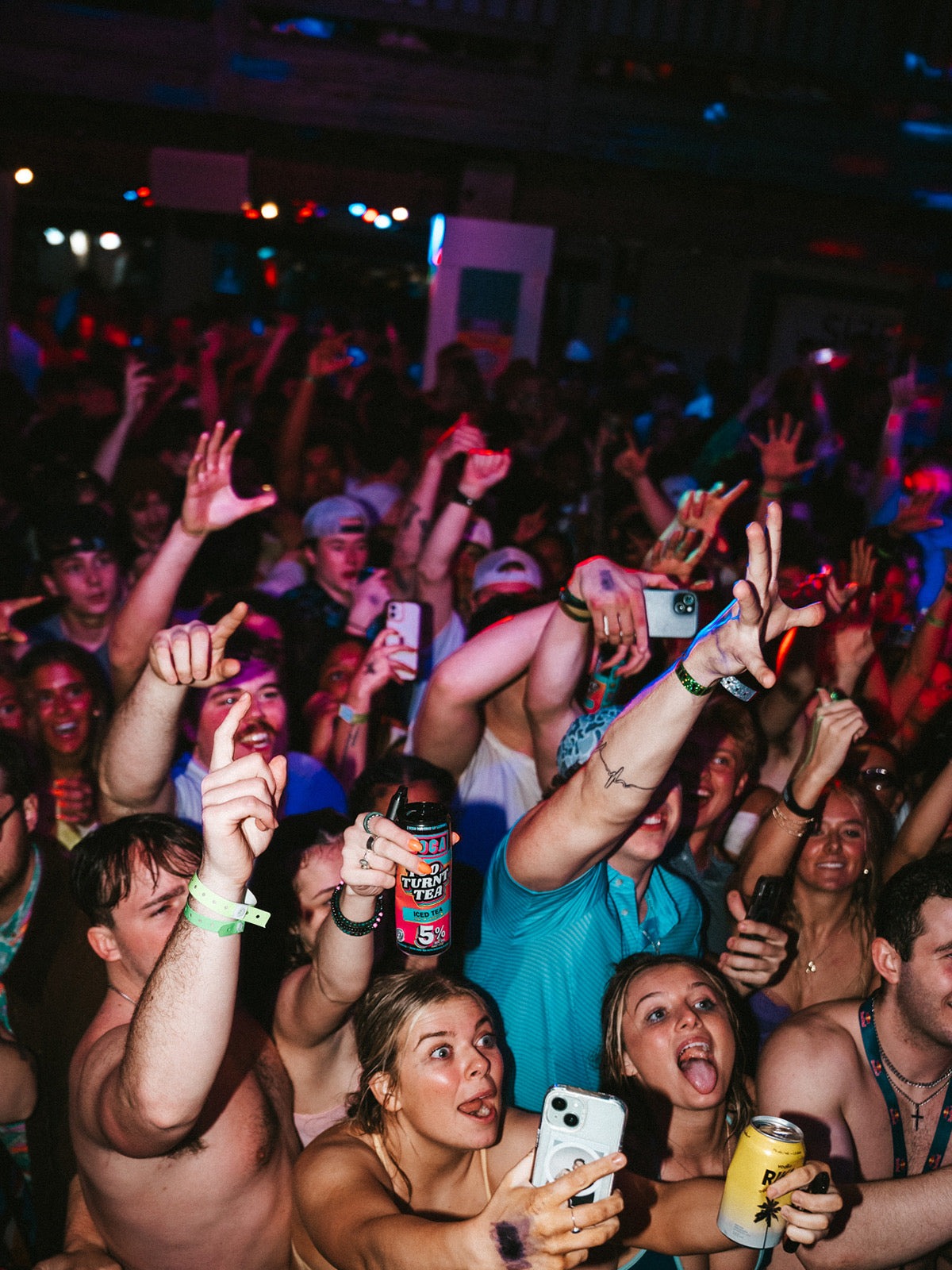 Crowd at a concert with people raising their hands and taking photos.