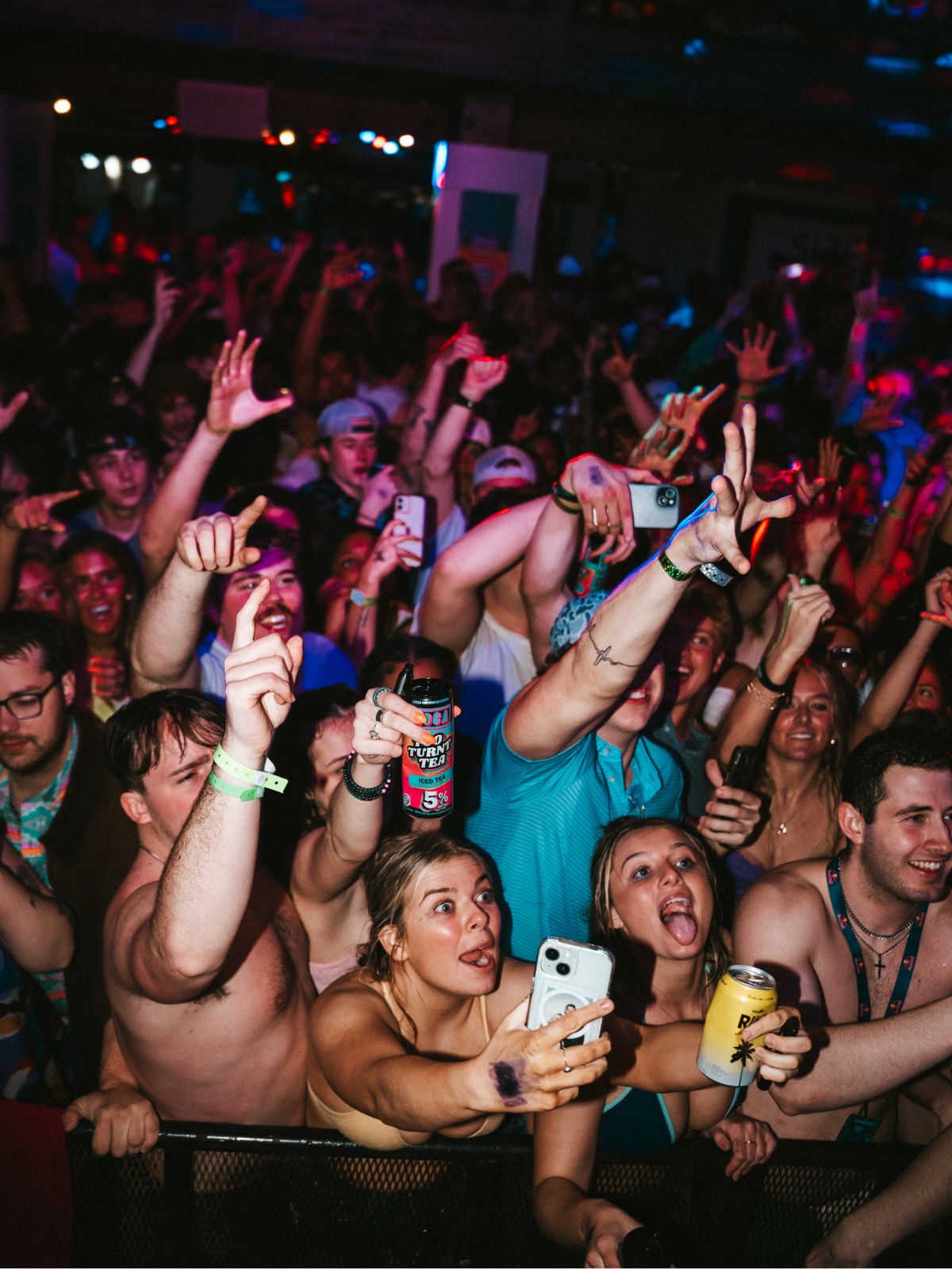 Crowd at a concert with people raising their hands and taking photos.