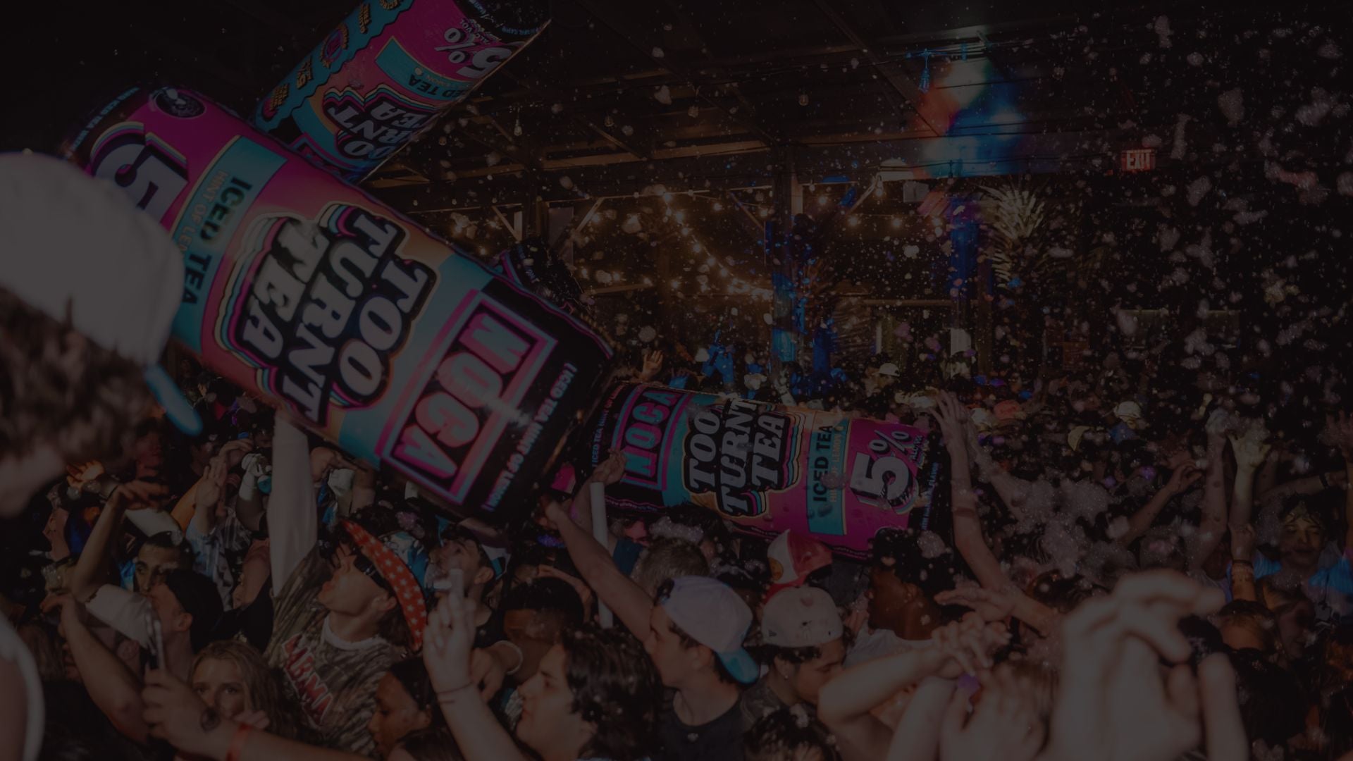 People holding large 'Too Turnt Tea' branded Blow Ups at a party with confetti in the air.